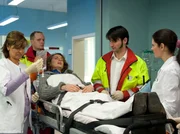 Jana Kraft (Marie Rönnebeck, liegend) wird nach einem Autounfall von den Notärzten (Komparsen) in die Sachsenklinik gebracht. Dort werden sie von Dr. Elena Eichhorn (Cheryl Shepard, rechts) und Schwester Yvonne (Maren Gilzer) in Empfang genommen.