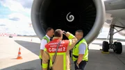 Ein Frachtflieger hebt ab, plötzlich kreuzt ein Vogelschwarm die Startbahn. Mehrere Tauben werden von den Triebwerken angesaugt. Ein Triebwerk hat was abbekommen. Der Pilot (li.) begutachtet mit einem Feuerwehrmann und einem Maintenance-Mitarbeiter das beschädigte Triebwerk.