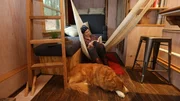 After completing her tiny house, builder, Sophie Clark, takes a moment to relax with a book in her hammock, with her faithful companion Whisky at her feet, in Seattle, Washington, as seen on Tiny House, Big Living.