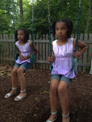 The Young Gibbons twins playing on swings.
