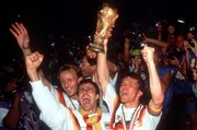 Lothar Matthäus, Pierre Littbarski und Andreas Brehme halten jubelnd den WM-Pokal hoch, Rom.