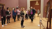 Lena (Jessica Lord, v. M.) steht im Museum wie angewurzelt vor einem Gemälde. Darauf sind sie und ihre Mutter abgebildet. Doch niemand darf wissen, dass es sich wirklich um ein Porträt von ihr aus dem Jahr 1905 handelt. Ihre Freunde Max (Rory J. Saper, l.), Ines (Eubha Akilade), Dash (Hiran Abeysekera), Jeff (Castle Rock Peters) und Thea (Hanna Dodd) und weitere Klassenkameraden (Statisten) und ihr Lehrer (Aron Bertetto) schauen ebenfalls sehr erstaunt auf das Bild.