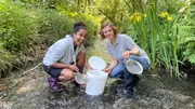 Pia (links) und Tanja Eybe erforschen einen Bach und die darin lebenden Insektenlarven. Dabei kommen einfache Küchensiebe zum Einsatz.