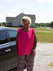 Milla stands next to her car.
