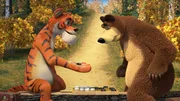 Der Bär spielt mit dem Tiger ein Brettspiel am See.
