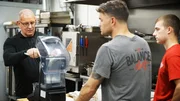 Chef Robert Irvine shows The Balanced Chef owner, Brian Donovan, along with kitchen manager, Kent Vedder, how to make new menu items, as seen on Restaurant Impossible, season 20