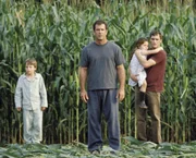 Fassungslos stehen (v.l.n.r.) Morgan (Rory Culkin), Graham (Mel Gibson), Bo (Abigail Breslin) und Merrill (Joaquin Phoenix) vor den r&auml;tselhaften Kornkreisen, die er auf seinem Feld entdeckt. Noch w&auml;hrend er die &Uuml;belt&auml;ter in seiner n&auml;heren Umgebung sucht, tauchen weltweit &auml;hnliche Ph&auml;nomene auf ...