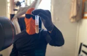 Masked subject holding a lab test tube. Masked subject holding a lab test tube.