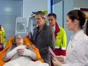 Die schwangere Natalie Trautmann (Astrid Posner, liegend) wird nach einem Wohnungsbrand von ihrem Mann Götz (Markus Böker, 3. von rechts) und einem Notarzt (Komparse) in die Sachsenklinik eingeliefert. Dr. Elena Eichhorn (Cheryl Shepard, rechts) wird sie und ihr Kind untersuchen.