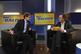 Tine (Theresa Scholze, l.) soll in der Talkshow von Hugo Egon Balder (Hugo Egon Balder, r.) ein wenig &uuml;ber Schw&auml;nze plaudern, als sie mit einer ungeheuren Neuigkeit an die &Ouml;ffentlichkeit geht ...
