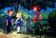 Pippi sitzt auf dem Zaun der Villa Kunterbunt und trifft Annika und Tommy, die auf dem Weg zur Schule sind.