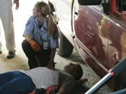 A paramedic sitting kneeling next to Karl's Levi's dead body in the garage.