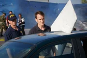 Agent Joe Sedor (played by Jason Faulkner) examines wreckage embedded in a car. (reconstitution)