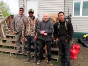 Charlie Wright, James Roberts, Joey Zuray and Stan Zuray stand outside a building with some hunting gear.