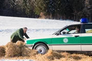 Girwidz (Michael Brandner) ist ungeduldig und möchte trotz defekter Bremse mit dem Streifenwagen weiterfahren; Hubert (Christian Tramitz) sitzt im Auto und lenkt. Girwidz (Michael Brandner) ist ungeduldig und möchte trotz defekter Bremse mit dem Streifenwagen weiterfahren; Hubert (Christian Tramitz) sitzt im Auto und lenkt.