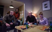 Daniel Lyons (Russell Tovey, l.), Fran Baxter (Sharon Duncan Brewster, 2.v.l.), Stephen Lyons (Rory Kinnear, M.) und Rosie Lyons (Ruth Madeley, r.) schauen die schockierenden Nachrichten im Fernsehen.