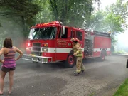 Commerce Township Fire Department arriving on the scene, while neighbors watch as the fire engulf the home.