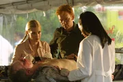 Die Gerichtsmedizinerin Alexx Woods (Khandi Alexander, r.) zeigt Calleigh (Emily Procter) und Horatio (David Caruso) eine Eintrittswunde in der Brust des Piloten. Wurde er erschossen? Wer hatte die Waffe mit an Bord?