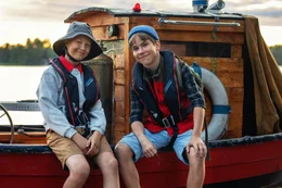 Pertsa (Olavi Kiiski) und Kilu (Oskari Mustikkaniemi) sitzen stolz vor ihrem Boot.
