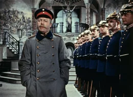 Bei einem Tr&ouml;dler erwirbt Wilhelm Voigt (Heinz R&uuml;hmann) eine gebrauchte Hauptmannsuniform. Nachdem er sie angezogen hat, erscheint er mit einem Schlag als anderer Mensch, denn alle erweisen dem uniformierten Hauptmann h&ouml;chsten Respekt.