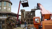 Behind the scenes of a camera operator filming the roof being lowered onto the house using the crane.