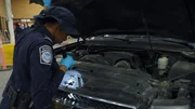 CBP-Beamter Thomas inspiziert mit einer Taschenlampe die Motorhaube des Fahrzeugs eines Passagiers am Einreisehafen von Hidalgo in Hidalgo, Texas. (National Geographic)