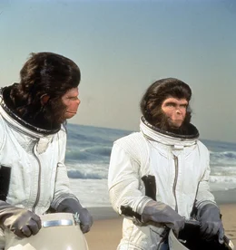 Dem intelligenten, der menschlichen Sprache m&auml;chtigen Schimpansenpaar Dr. Cornelius (Roddy McDowall, r.) und Dr. Zira und Dr. Milo (Sal Mineo, l.) gelingt mit einem notgelandeten US-Raumschiff die Flucht vom Planet der Affen. Sie begeben sich auf eine Zeitreise und landen schlie&szlig;lich in der Gegenwart an der K&uuml;ste von Los Angeles ...