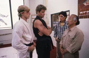 Um der brutalen Schikane ein Ende zu bereiten, setzt sich Mr. Miyagi (Pat Morita, r.) f&uuml;r Daniel (Ralph Macchio, 2.v.r.) ein. Doch Johnny Lawrence (William Zabka, l.) und sein Karate-Meister John Kreese (Martin Kove, 2.v.r.) kennen keine Gnade.