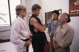 Um der brutalen Schikane ein Ende zu bereiten, setzt sich Mr. Miyagi (Pat Morita, r.) f&uuml;r Daniel (Ralph Macchio, 2.v.r.) ein. Doch Johnny Lawrence (William Zabka, l.) und sein Karate-Meister John Kreese (Martin Kove, 2.v.r.) kennen keine Gnade.