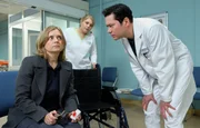 Sylvia Haas (Nina Weniger, li.) kommt mit einer Schnittwunde unter dem Auge, die angeblich von einem heruntergefallenen Bild stammt, in die Sachsenklinik. Dr. Philipp Brentano (Thomas Koch, re.) will die Wunde behandeln und bittet Schwester Miriam (Christina Petersen, mi.) einen Rollstuhl zu bringen. Sylvia scheint sehr wackelig auf den Beinen zu sein.
