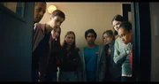 Von links: Fischer (Fayez Bakhsh), Louis (Oliver Cunliffe), Kaz (Maiya Silveston), Meg (Katy Byrne), Glen (Krish Misra), Bea (Aoife Hughes), Isabel (Alis Waters) und Faye (Keira Chansa,) schauen in das kleine Zimmer hinein, in dem das Alien sitzt. Es kann die Gestalt verändern und aussehen wie jede Person.