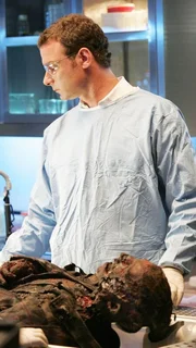 Michael Keppler (Liev Schreiber) untersucht eine völlig verkohlte Leiche, die nach einem Brand in der Fabrikhalle eines Schrottverwerters gefunden wurde.