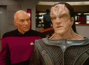 Captain Picard (Patrick Stewart) verhandelt mit Lutan (Jessie Lawrence Fergus), dem Haeuptling des Planeten Ligon II. Picard möchte einen Impfstoff von Lutan bekommen, den es nur auf Ligon II gibt.