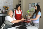 Maja entschuldigt sich bei Ulla mit einem Präsentkorb aus dem Dorfladen. Von Links: Ulla (Sabrina Dietel, KLD), Rosi (Brigitte Walbrun), Maja (Godiva Adela).