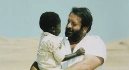 Bei seinen gefahrenreichen Nachforschungen wird der schlagkr&auml;ftige Polizist Plattfu&szlig; (Bud Spencer, r.) von dem kleinen Bodo (Baldwyn Dakile, l.) unterst&uuml;tzt.