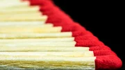 Side view of a row of wooden matches aligned on a black background