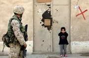 Falludscha, Irak, 2005: Ein irakisches M&auml;dchen h&auml;lt sich die Ohren zu, als ein Marine der Ersten Division im Zentrum der schwer bewachten Stadt Falludscha patrouilliert.