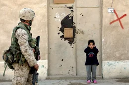 Falludscha, Irak, 2005: Ein irakisches M&auml;dchen h&auml;lt sich die Ohren zu, als ein Marine der Ersten Division im Zentrum der schwer bewachten Stadt Falludscha patrouilliert.