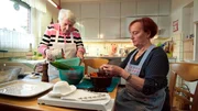 Frau Schubert mit ihrer Freundin bei Küchenarbeit.