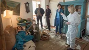 Eine Explosion hat ein Wismarer Wohngebiet gehörig erschüttert. Die Kollegen der Kripo rücken an, denn leider ist Barbara Voss (Ulrike Lodwig, l.) Opfer der Explosion geworden. Offenbar ist eine Gewehrgranate aus dem Zweiten Weltkrieg im Ofen hochgegangen. Handelt es sich um einen Unfall oder war es ein gezielter Angriff auf die hilflose Frau? Die Ermittler Pöhlmann (Dominic Boeer, 3.v.l.), Karoline Joost (Nike Fuhrmann, 2.v.r.) und Timmermann (Mathias Junge, 3.v.r.) lauschen den ersten Erkenntnissen von Dr. Helene Sturbeck (Katharina Blaschke, 2.v.l.) und KTU-Leiterin Silke Matthias (Roswitha Prinzler, r.).