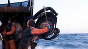 Deckhands work the block aboard the F/V Time Bandit.