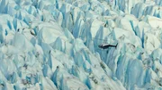 Ein Hubschrauber fliegt über einen verschneiten Berg in Alaska