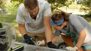 Kathrin and Tyler apply a piece of solder with a small torch to connect two pieces of aluminum, square stock that will be used to create the track system for the sliding, stowaway deck on the end of their tiny home, in Rossville, Georgia, as seen on Tiny House, Big Living.
