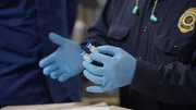 Ein FDA-Beamter hält zwei Fläschchen mit möglicherweise gefälschtem Botox in der Hand und untersucht sie. Die Fläschchen wurden in einer Lieferung gefunden.