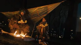 Ama (Amani-Jean Philippe) und ein Griot (Kenneth Herdigein), sitzen am Lagerfeuer, w&auml;rmen sich und essen Fisch. Der Griot erz&auml;hlt Ama Geschichten &uuml;ber Totem-Tiere.