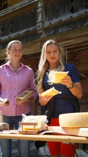 Moderatorin Iris Pohl (r.) mit Brigitte Kern vor Tisch. Iris hält Hornkäse in den Händen. Moderatorin Iris Pohl (r.) mit Brigitte Kern vor Tisch. Iris hält Hornkäse in den Händen.