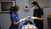 Dr. Sandra Lee performs surgery on Krystal W.'s forehead cyst with the aid of her assistant, Janet C.