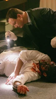 Detective Taylor (Gary Sinise) untersucht das Opfer (Tony Daly) einer blutigen Schießerei. Detective Taylor (Gary Sinise) untersucht das Opfer (Tony Daly) einer blutigen Schießerei.