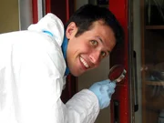 Willi Weitzel ist mit der Lupe auf der Suche nach Spuren, nachdem in dem Reihenhaus eingebrochen wurde.