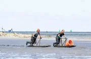Mit dem Holzschlitten gleiten Frank Buchholz (l) und Austernfischerin Barbara Rodenburg durchs Wattenmeer. Mit dem Holzschlitten gleiten Frank Buchholz (l) und Austernfischerin Barbara Rodenburg durchs Wattenmeer.
